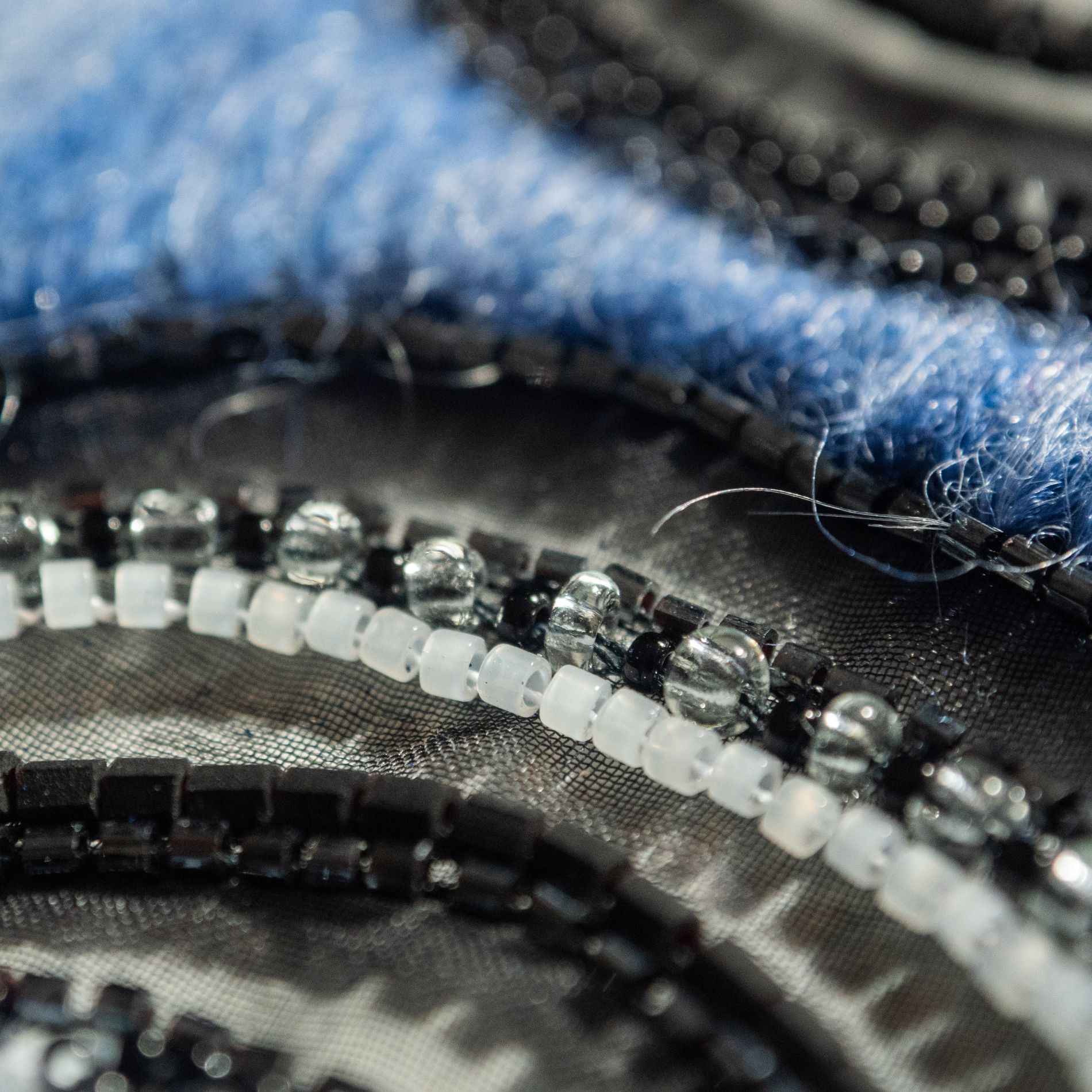 Chanel 2018 Luneville Embroidery Detail – Mohair and Beads Close-up of a Luneville embroidery sample inspired by Chanel Pre-Fall 2018, showing blue mohair, black bugle beads, clear glass beads, and matte white seed beads stitched on fine tulle.