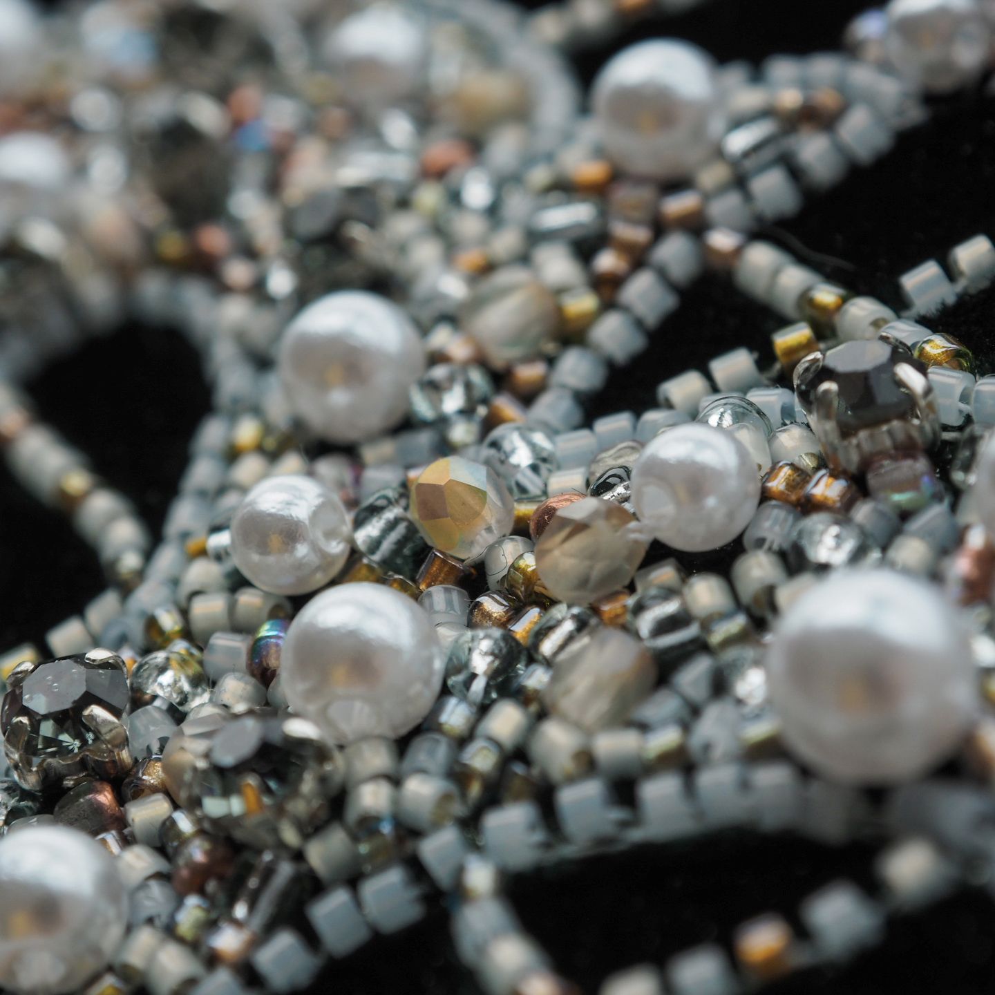 Couture Luneville Embroidery Detail – Pearls and Beadwork on Velvet Close-up of couture Luneville embroidery with pearls, faceted beads, and seed bead lines stitched on black velvet.