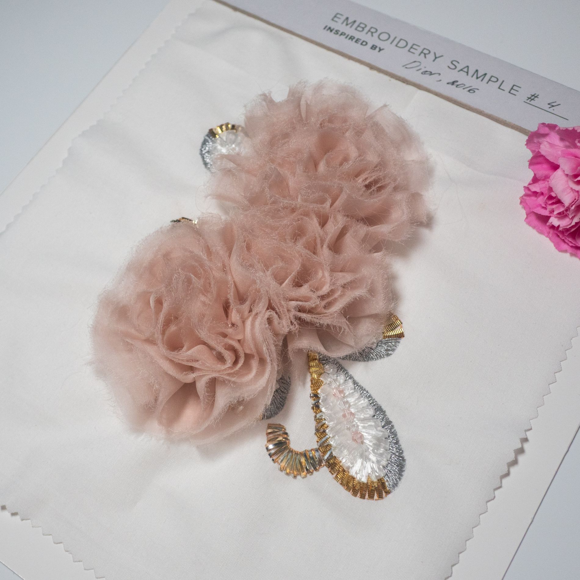 Dior 2016 3D Tulle Flower Embroidery Study Couture embroidery sample inspired by Dior 2016, featuring layered 3D tulle flowers with gold and silver sequin and thread detailing on a white fabric base.