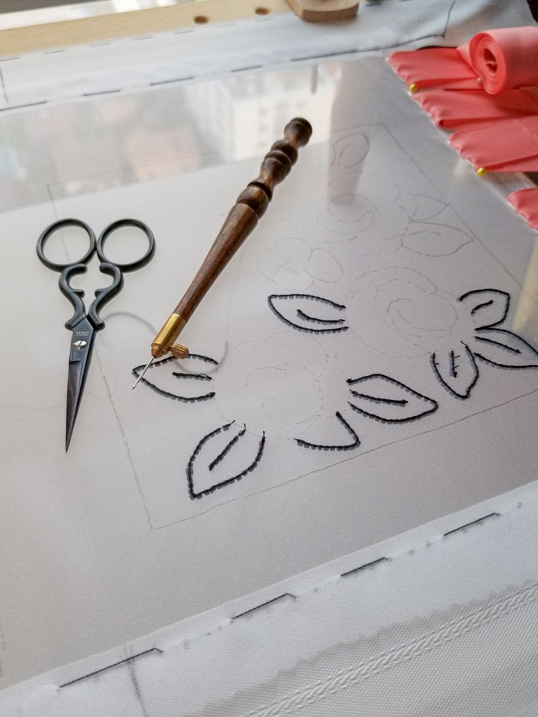 Luneville Embroidery Setup – Frame, Hook and Design Outline Luneville embroidery setup showing a wooden Luneville hook, embroidery scissors, and the outlined design on stretched organza, ready for tambour stitching.