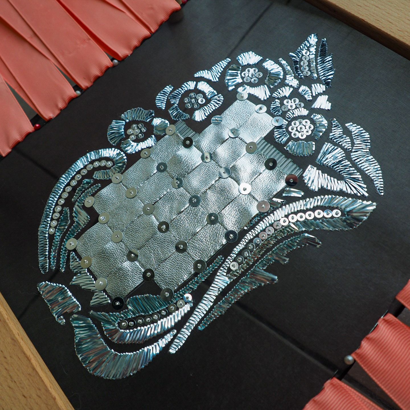 Schiaparelli 1938 Couture Embroidery Study – Mirror Panel Couture embroidery sample inspired by Elsa Schiaparelli’s 1938–39 evening jacket, featuring a mirrored central panel with silver metal strips, sequins and stylised floral motifs on black fabric.