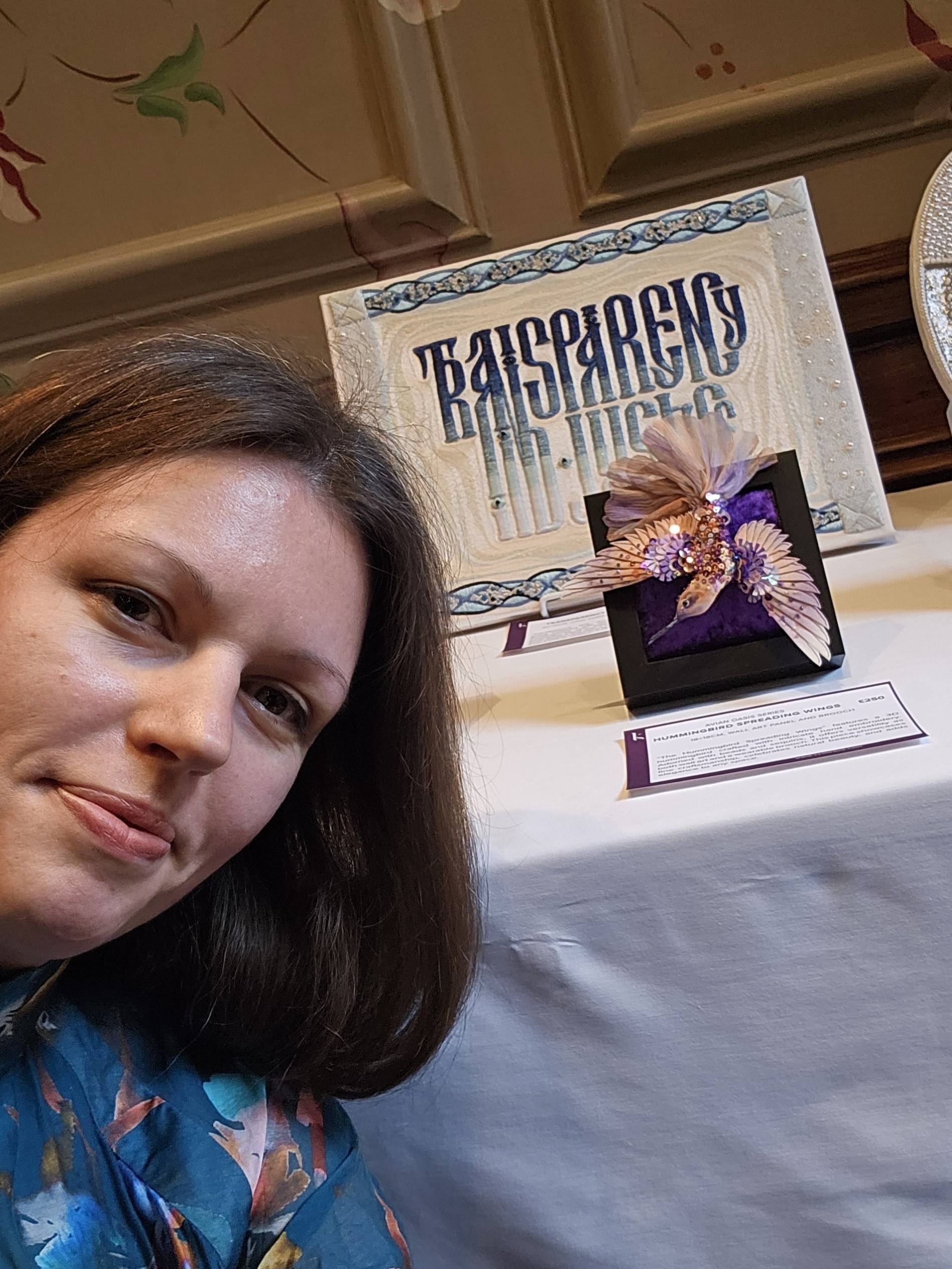 Hummingbird embroidery at HelvetArt Ksenia Semirova beside her framed hummingbird embroidery at the HelvetArt Art Fair in Reading