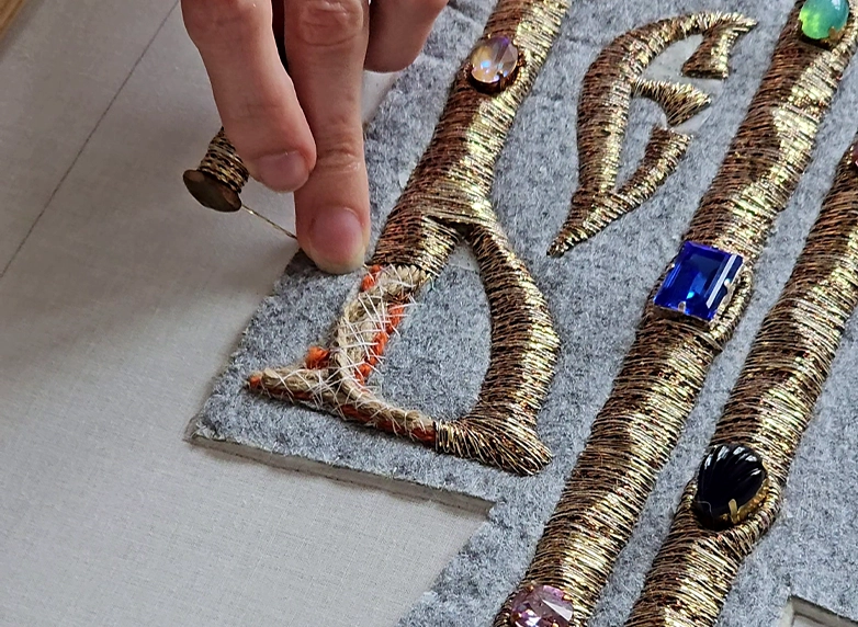 Believe – Goldwork Embroidery in Progress, Vyaz Lettering | Ksenia Semirova. Embroidery art Work in progress shot of Believe by Ksenia Semirova, showing Vyaz calligraphy formed with goldwork and tambour embroidery over metallic textile.