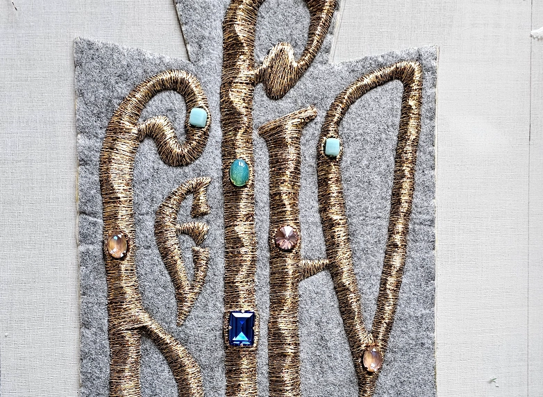 Believe – Vyaz Goldwork Embroidery Work in Progress | Ksenia Semirova. Embroidery art Embroidery in progress showing Vyaz lettering stitched with gold thread on dark textile background by artist Ksenia Semirova.