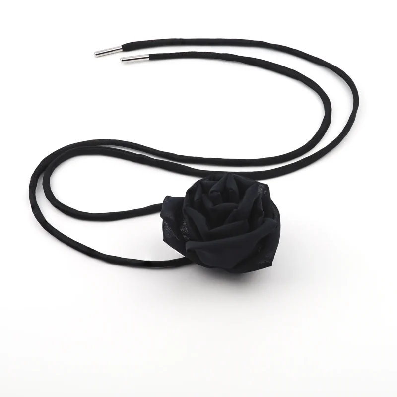 Image of a handmade black silk rose choker with a detailed black silk rose centerpiece and adjustable black satin lace, laid flat for display. Perfect for versatile styling and elegant outfits