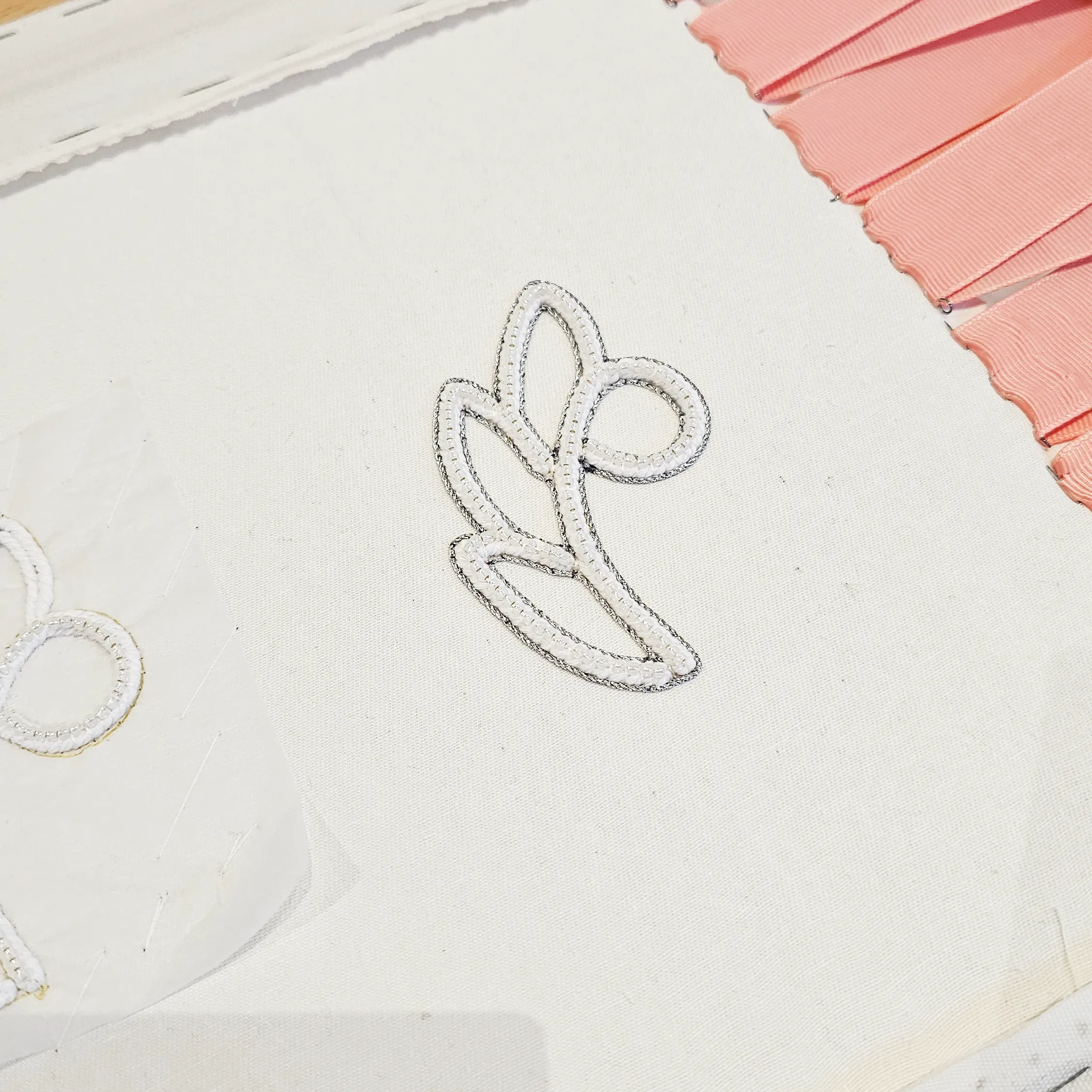 Pearl Embroidery Demonstration at SoShiro Gallery | Ksenia Semirova. Embroidery art Close-up of pearl embroidery featuring a white, structured floral pattern on fabric, with precise stitching and intricate pearl setting