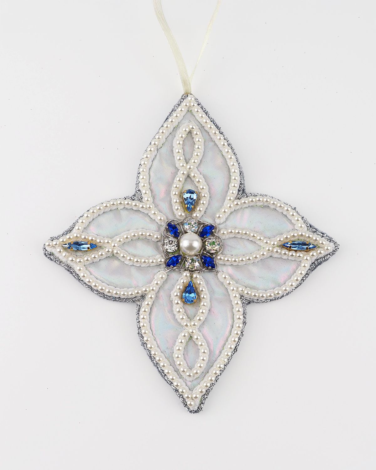 Hand-embroidered four-pointed ornament from the Jewels of Winter series by Ksenia Semirova, featuring white beadwork, blue crystals, and pearl-setting technique.