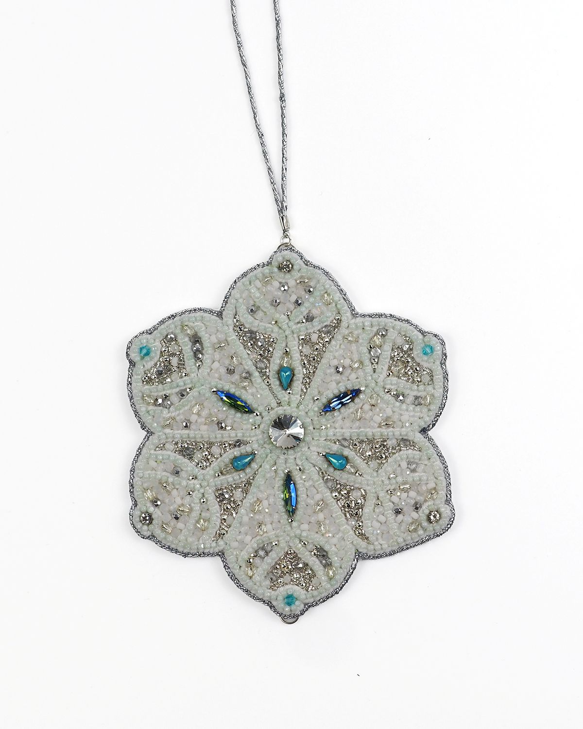 Hand-embroidered six-pointed snowflake ornament from the Jewels of Winter series by Ksenia Semirova, featuring white and silver beadwork with turquoise crystal details.