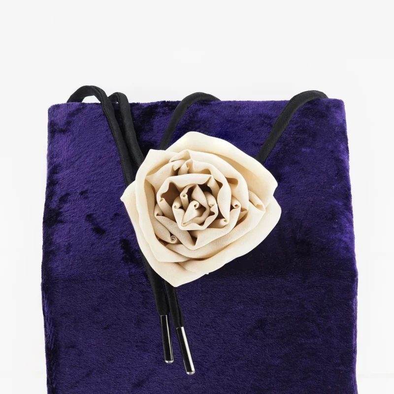 Handcrafted nude silk rose choker by Ksenia Semirova, featuring a delicate silk rose centerpiece and adjustable black satin lace with nickel-free metal ends, displayed on a luxurious purple backdrop. Perfect for elegant styling and timeless craftsmanship.