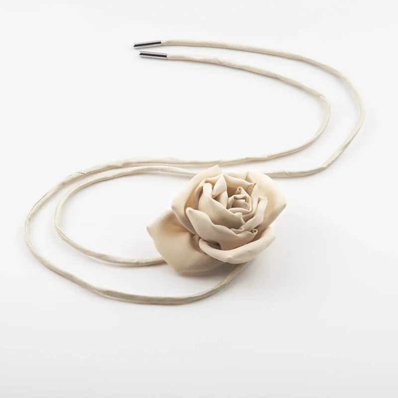 Image of a handmade nude silk rose choker with a detailed nude silk rose centerpiece and adjustable nude natural silk dupioni lace, laid flat for display. Perfect for versatile styling and elegant outfits