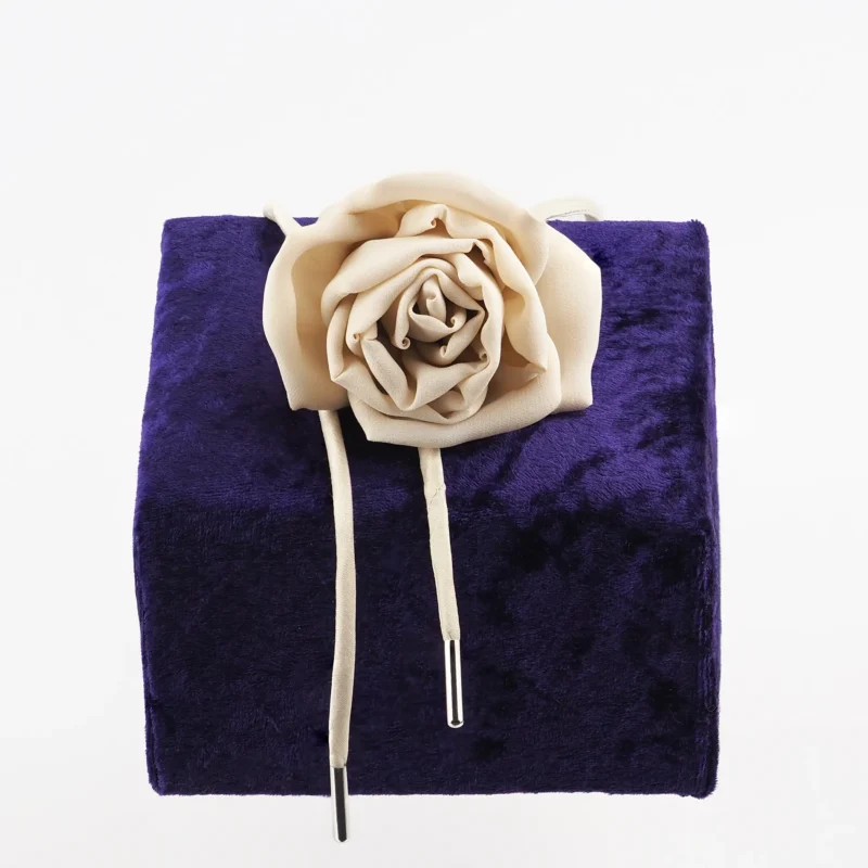 Handcrafted nude silk rose choker by Ksenia Semirova, featuring a delicate silk rose centerpiece and adjustable nude dupioni silk lace with nickel-free metal ends, displayed on a luxurious purple backdrop. Perfect for elegant styling and timeless craftsmanship.