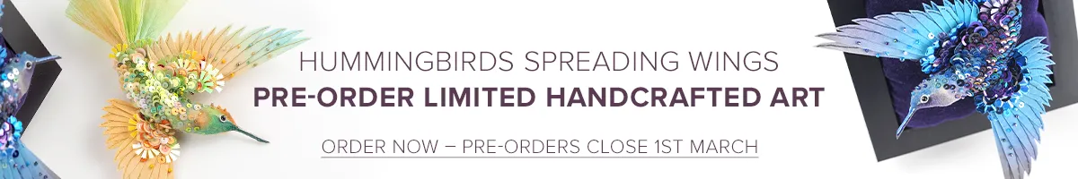 Two handcrafted hummingbirds made with hand-dyed silk, sequins, and beads. One bird in vibrant blue tones is mounted on a velvet frame, while the other in green and gold hues lies beside it. Part of the Hummingbirds Spreading Wings limited handcrafted art pre-order collection