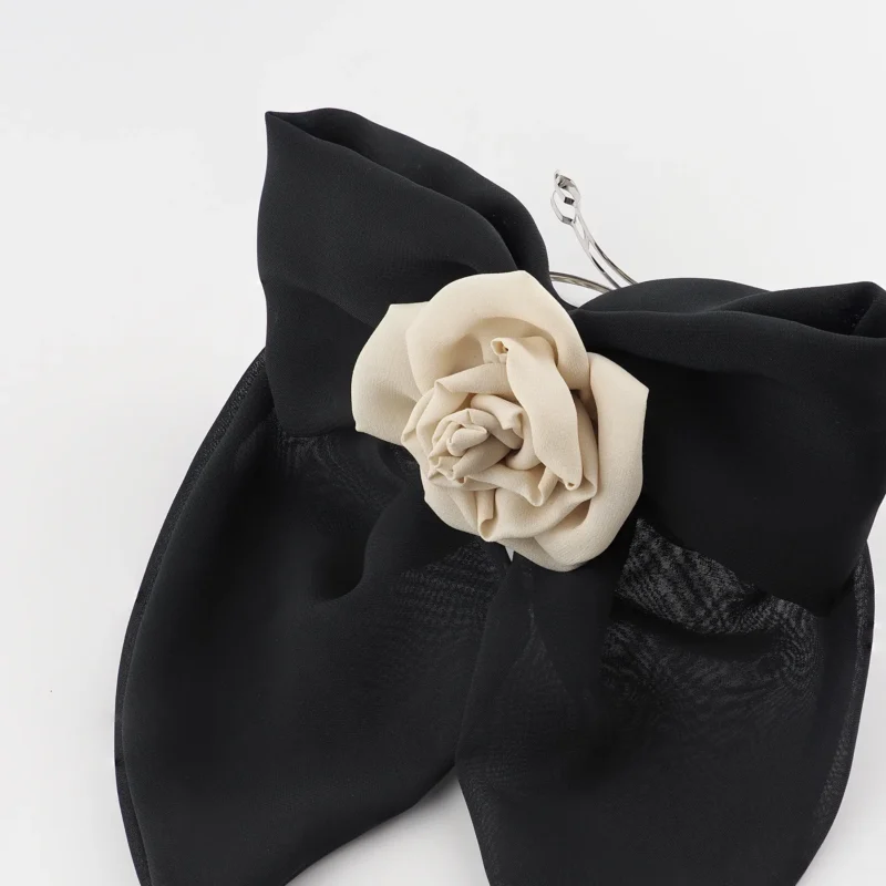 Close-up of a black chiffon bow hair clip with a handmade nude chiffon rose centerpiece, designed as a bold yet elegant accessory for versatile hairstyles