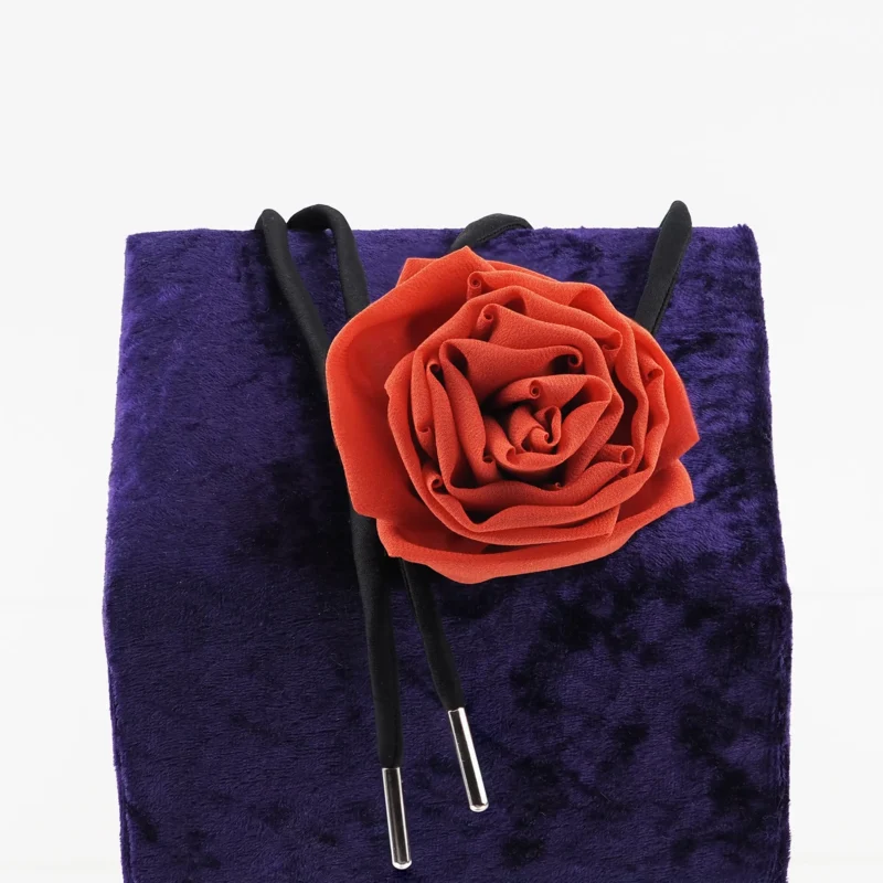 Handcrafted red silk rose choker by Ksenia Semirova, featuring a delicate silk rose centerpiece and adjustable black satin lace with nickel-free metal ends, displayed on a luxurious purple backdrop. Perfect for elegant styling and timeless craftsmanship.