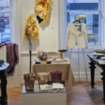 SoShiro Gallery display featuring hand embroidery work, including a white jacket with pearl embroidery, embroidery samples, and tools on a table