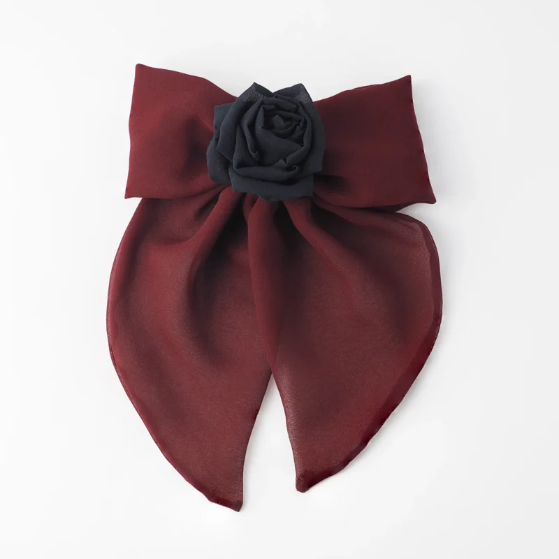 Handmade maroon chiffon bow hair clip featuring a large, elegant bow with soft flowing tails and adorned with a black silk rose at the center. Perfect for gothic and romantic styles