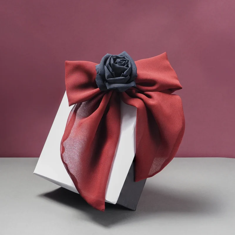 Handmade silk bow hair clip in deep red with a black silk rose centerpiece, presented on a stylish gift box. A luxurious and elegant accessory for gothic, romantic, or alternative fashion. Perfect for gifting or adding a statement touch to hairstyles