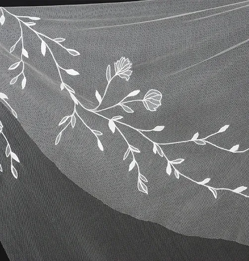 Close-up of floral tambour lace motif on fine tulle, part of a bespoke embroidered wedding veil.