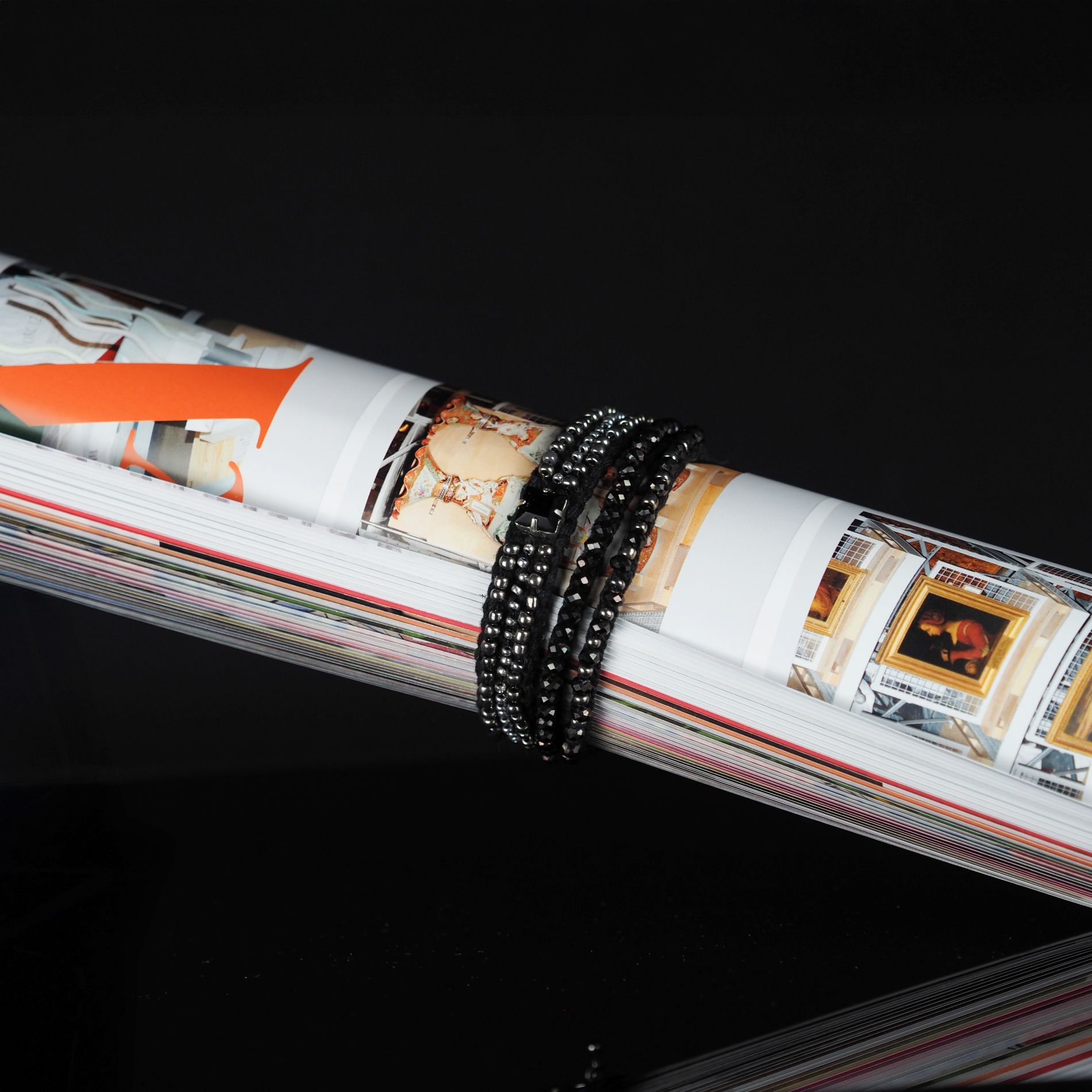 Heritage Craft Beaded Bracelet Black Silver Design | Ksenia Semirova. Embroidery art Black and silver beaded bracelet with multiple strands, created using pearl setting embroidery, wrapped around a rolled magazine with art illustrations.