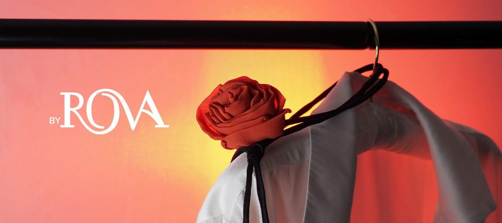Silk rose choker by By Rova styled on a white blouse with dramatic red and orange lighting in the background
