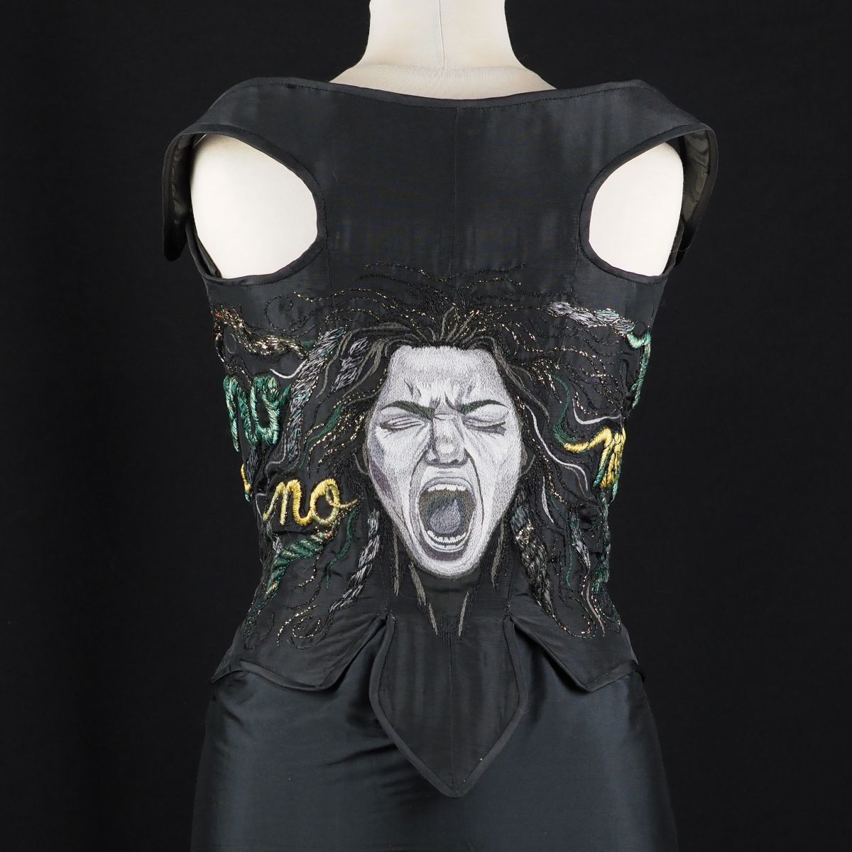 Back view of corset showing hand-embroidered screaming face and repeated “No” motifs on black fabric, displayed on a mannequin, from The Power of No by Ksenia Semirova