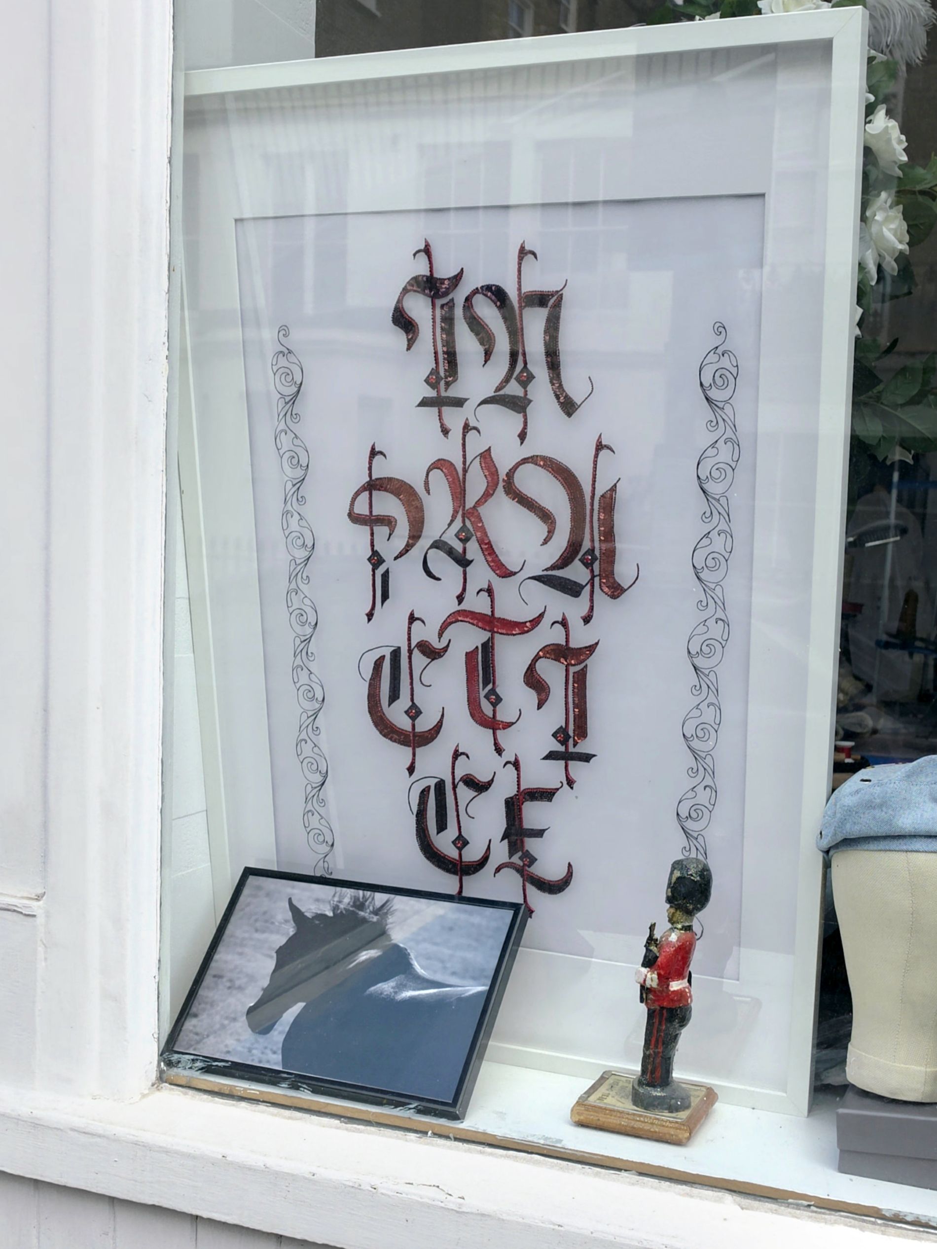 In Practice Displayed in Pimlico Studio Window In Practice displayed in a studio window in Pimlico, showing the framed Luneville embroidery composition in context.