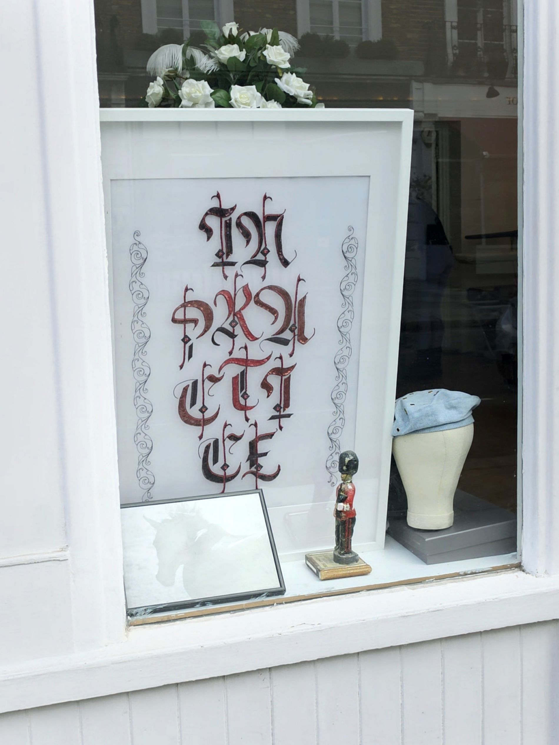 In Practice Studio Window Display in London Wider view of In Practice displayed in a London studio window, with the framed gothic lettering embroidery shown in context.