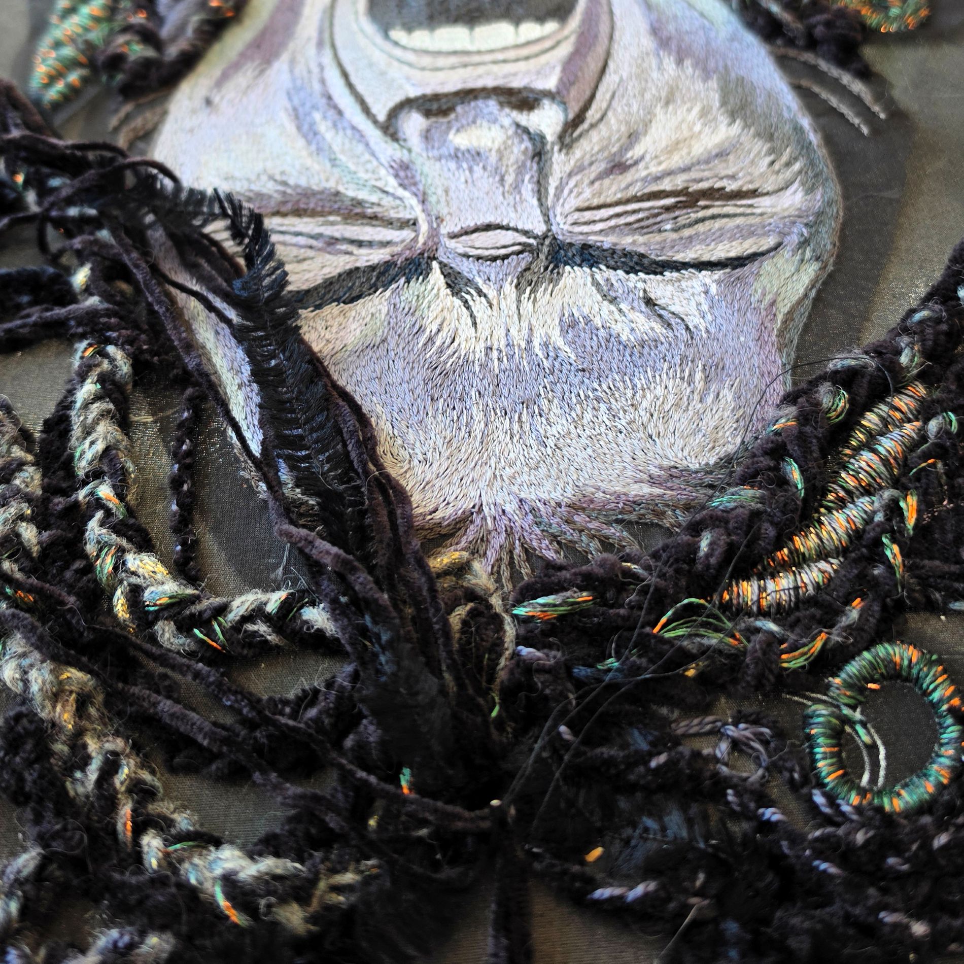 Close-up detail of Despair from the Power of No series, showing hand embroidered portrait stitching and layered black textile elements.