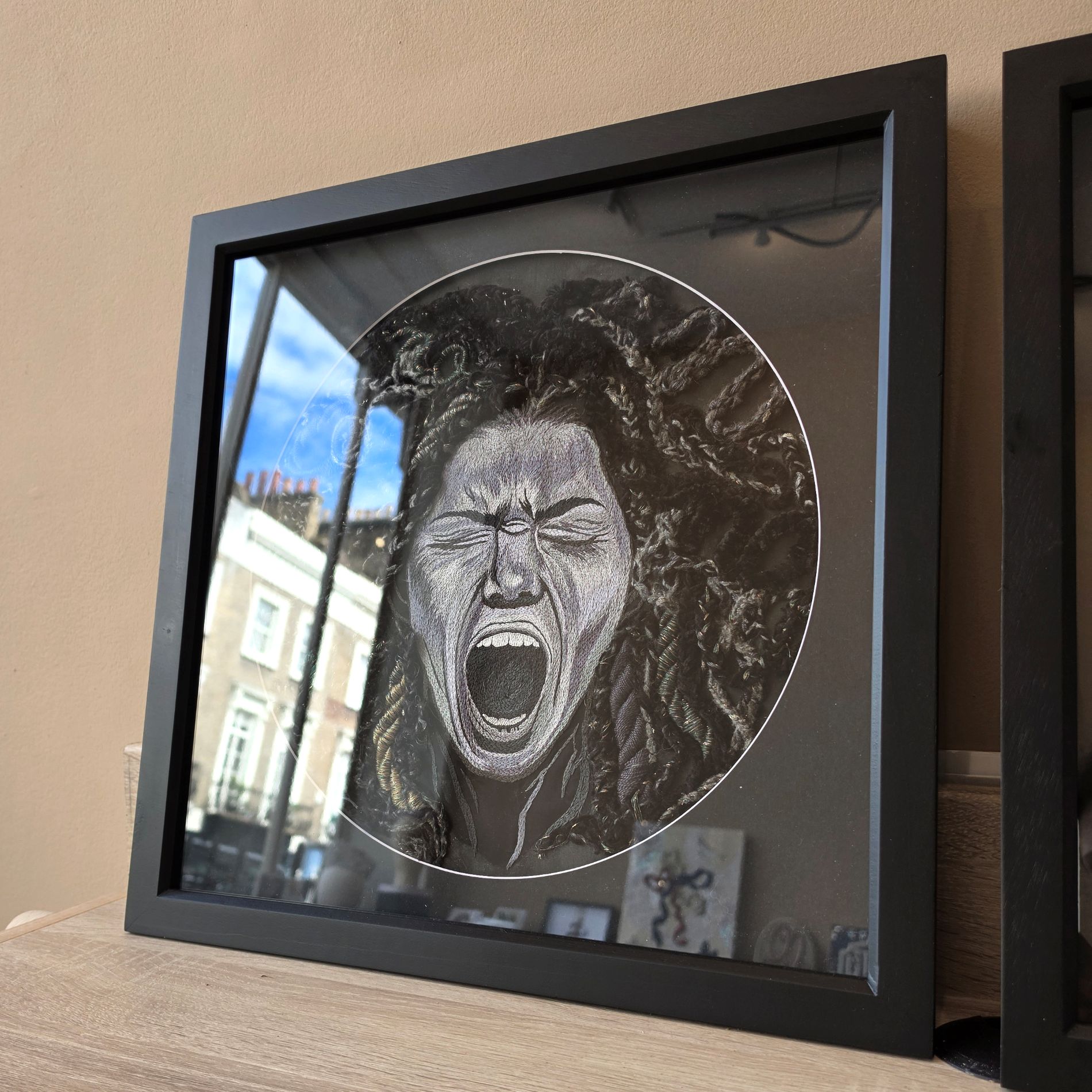 Framed hand embroidered textile artwork Despair from Ksenia Semirova’s Power of No series, showing a screaming stitched portrait in a black frame.