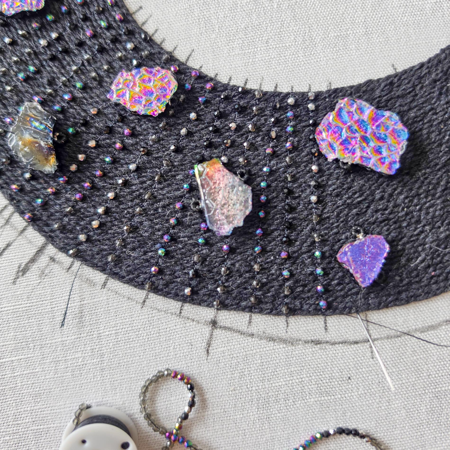 Close-up of the black To the Moon and Back necklace with colourful glass elements and fine bead embroidery.