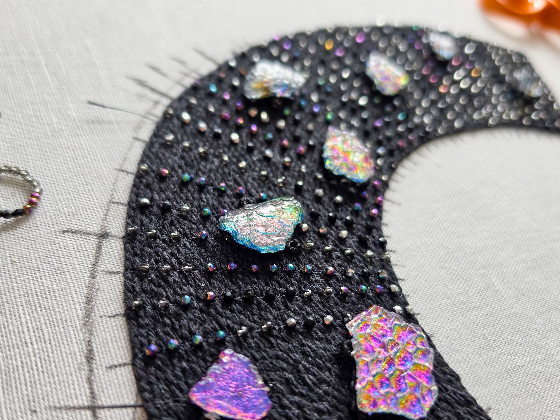 Close-up of the black To the Moon and Back necklace in progress, with pearl setting embroidery, iridescent beads and handmade dichroic glass elements.